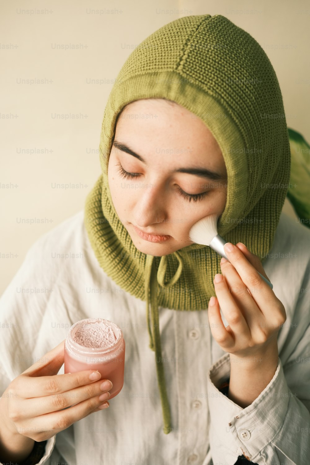 a woman in a green hat brushes her teeth