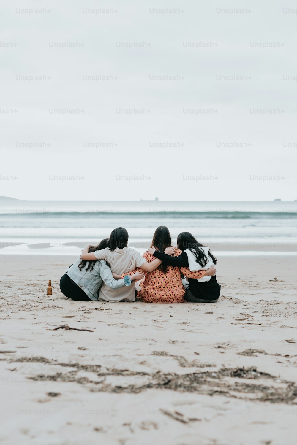 a group of people sitting on top of a sandy beach