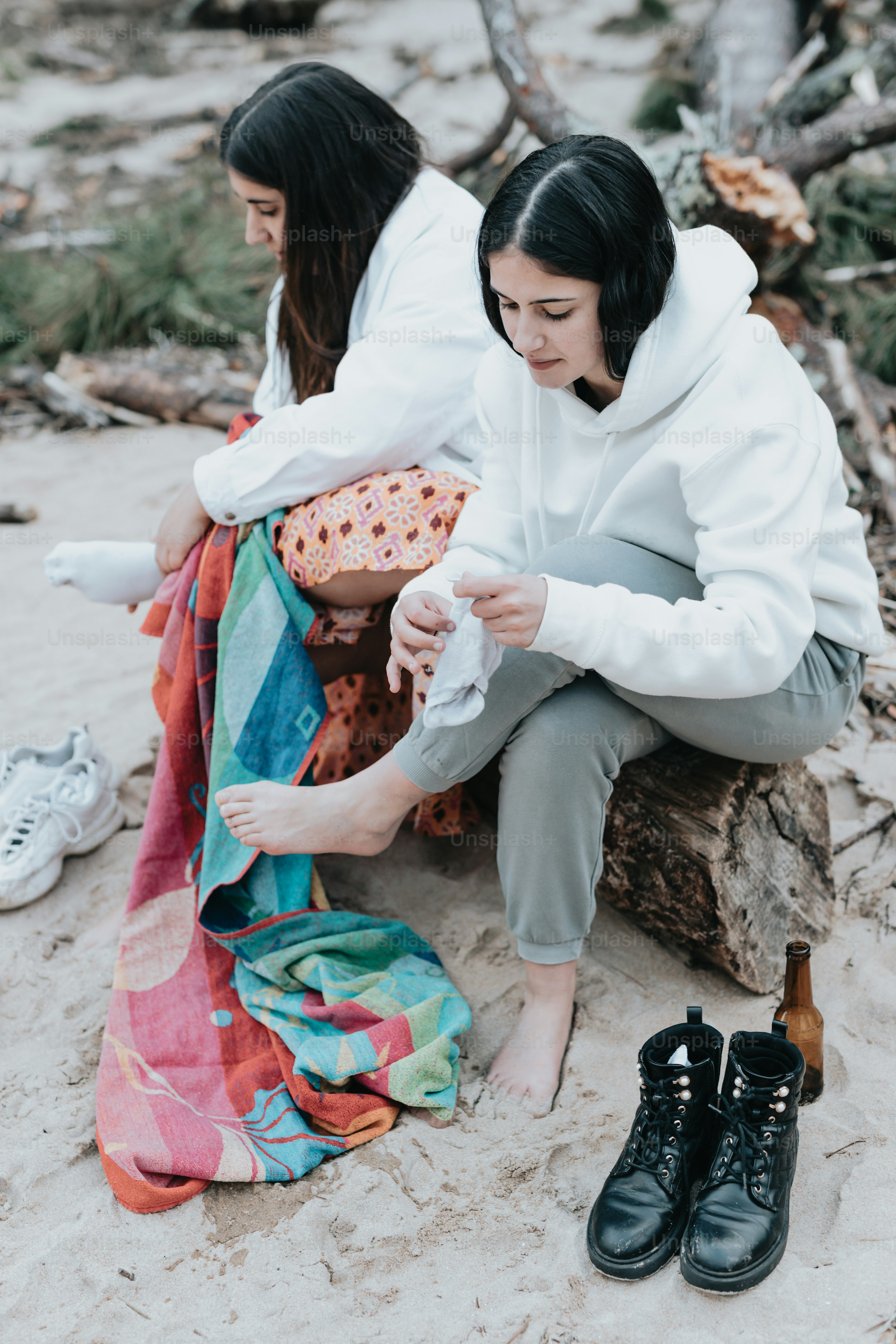 a couple of women sitting on top of a sandy beach