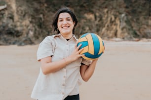 a woman holding a volleyball ball on a beach