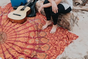 a woman sitting on a blanket next to a guitar