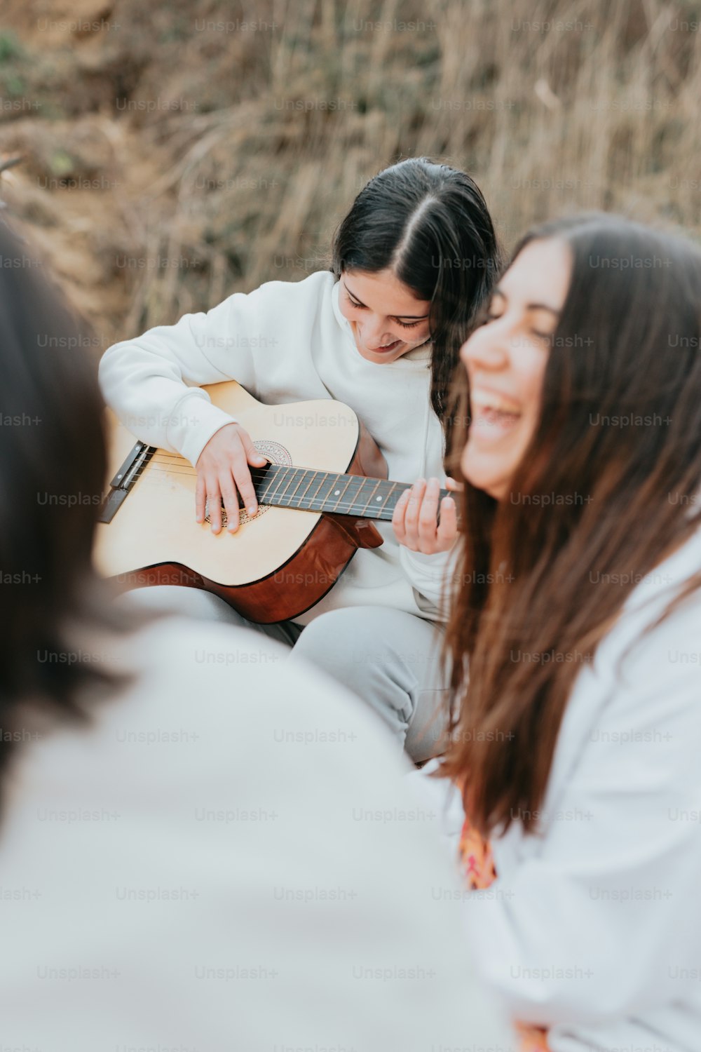 Una mujer tocando una guitarra mientras otra mujer mira