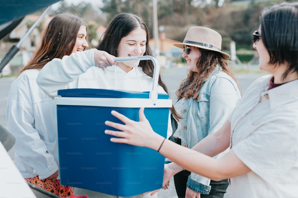 a group of women standing around a blue cooler
