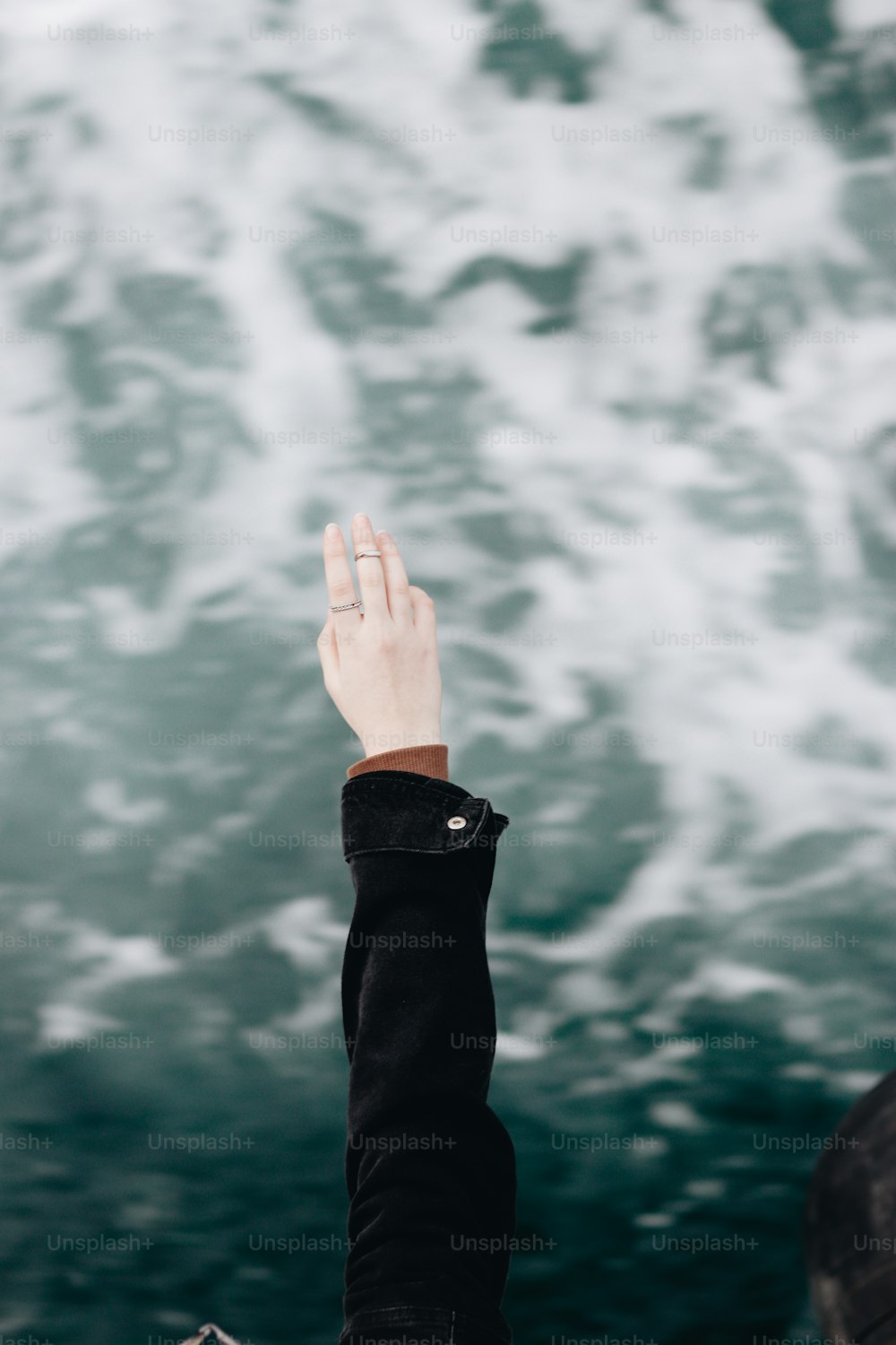 a person holding their hand up to the water