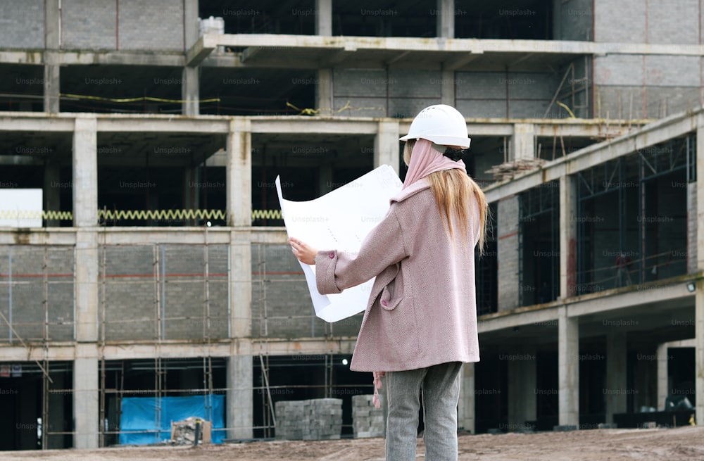 a woman in a hard hat is holding a blueprint