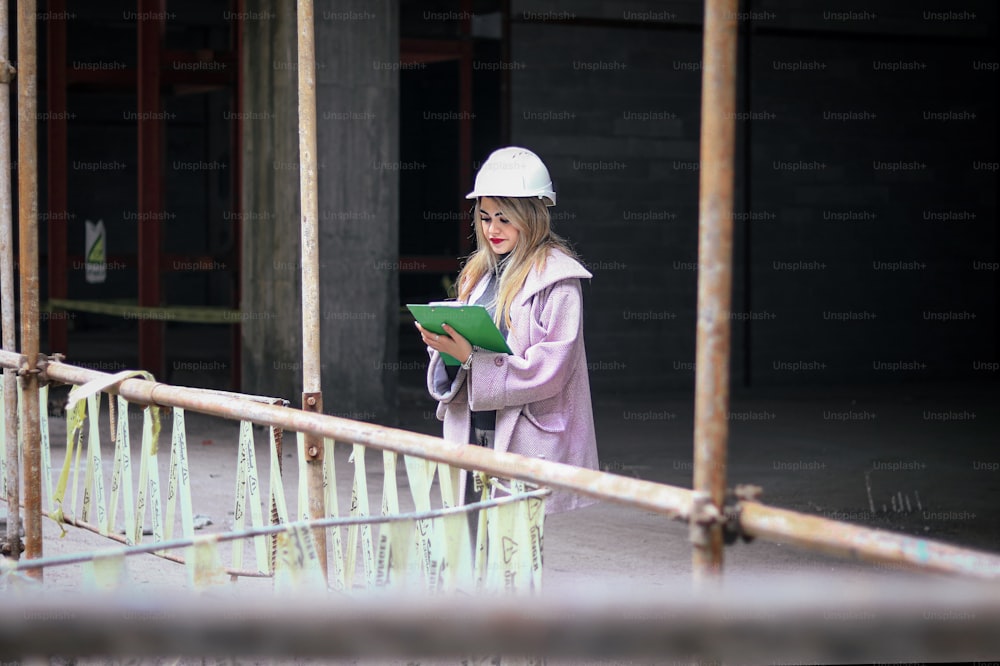 a woman wearing a hard hat and holding a green folder