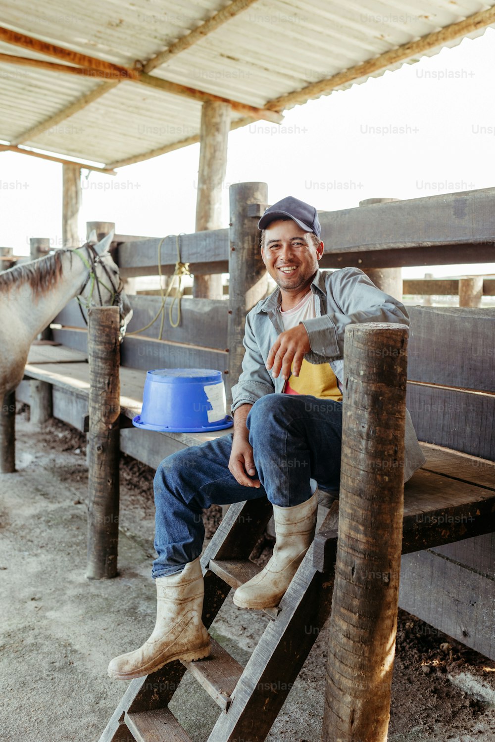 a man sitting on a wooden bench next to a horse