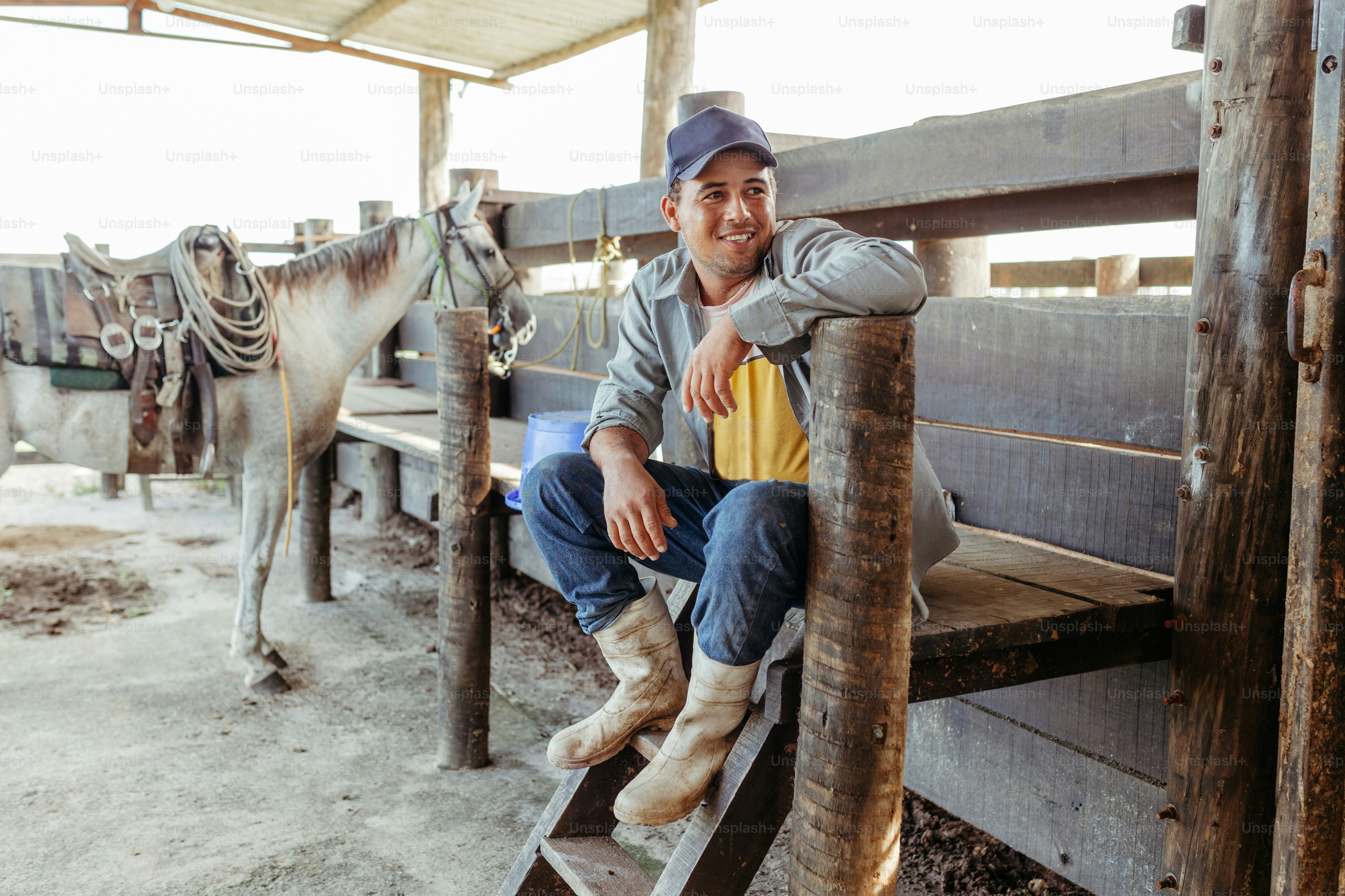 a man sitting on a wooden bench next to a horse