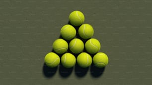 une pyramide de balles de tennis sur une surface verte