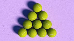 a pile of tennis balls sitting on top of a purple surface