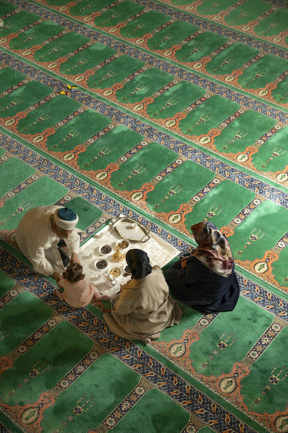 Eine Gruppe von Menschen sitzt auf einem grünen Teppich