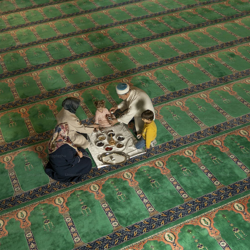a group of people sitting around a table on a rug