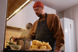 Un homme en tablier cuisant de la nourriture sur un poêle