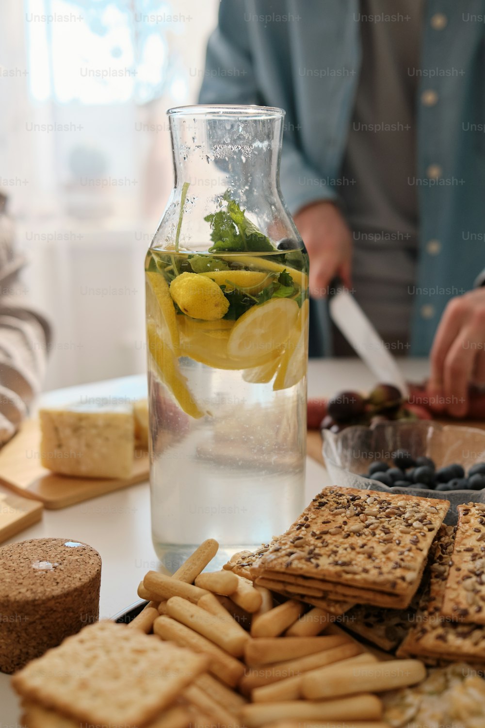 a pitcher of water with lemon slices and crackers