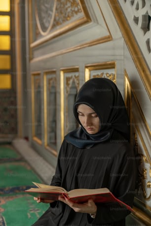 a woman in a black hijab is reading a book
