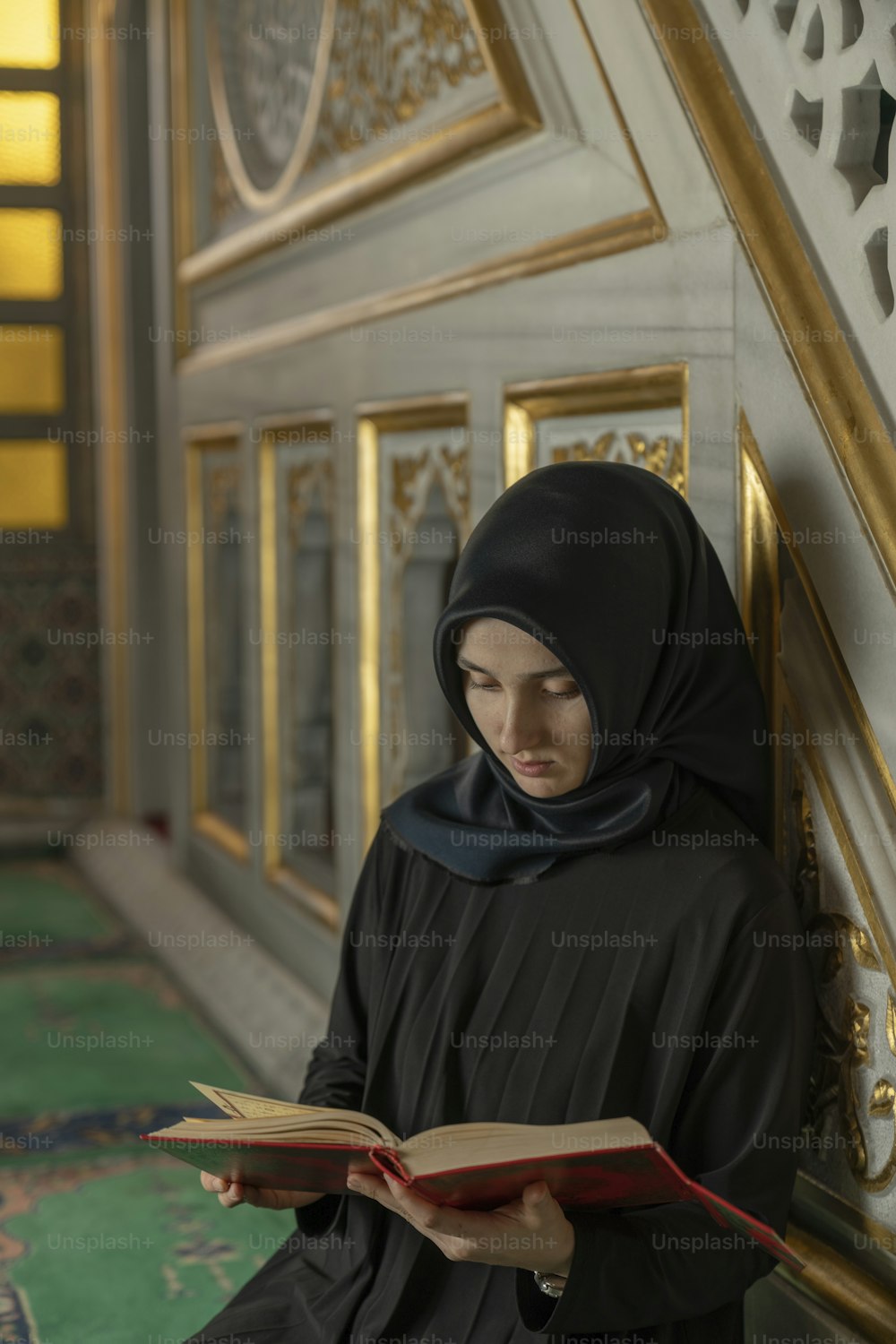Una mujer con un hijab negro está leyendo un libro