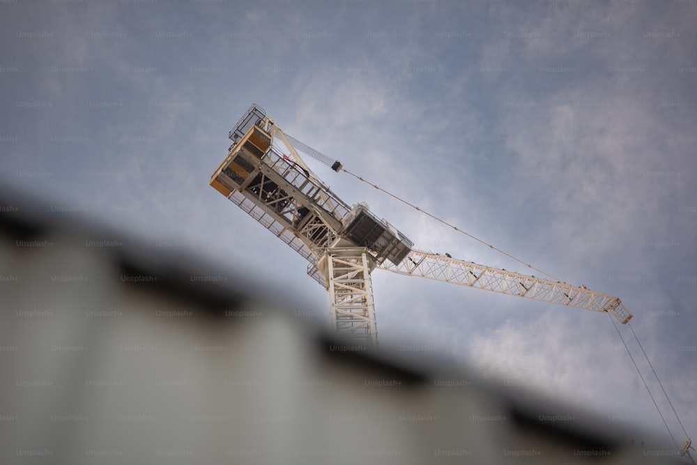 a tower crane is seen against a cloudy sky