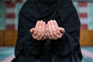 a person in a black outfit is holding their hands together