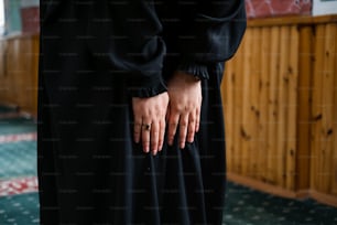 a woman in a black dress holding her hands together