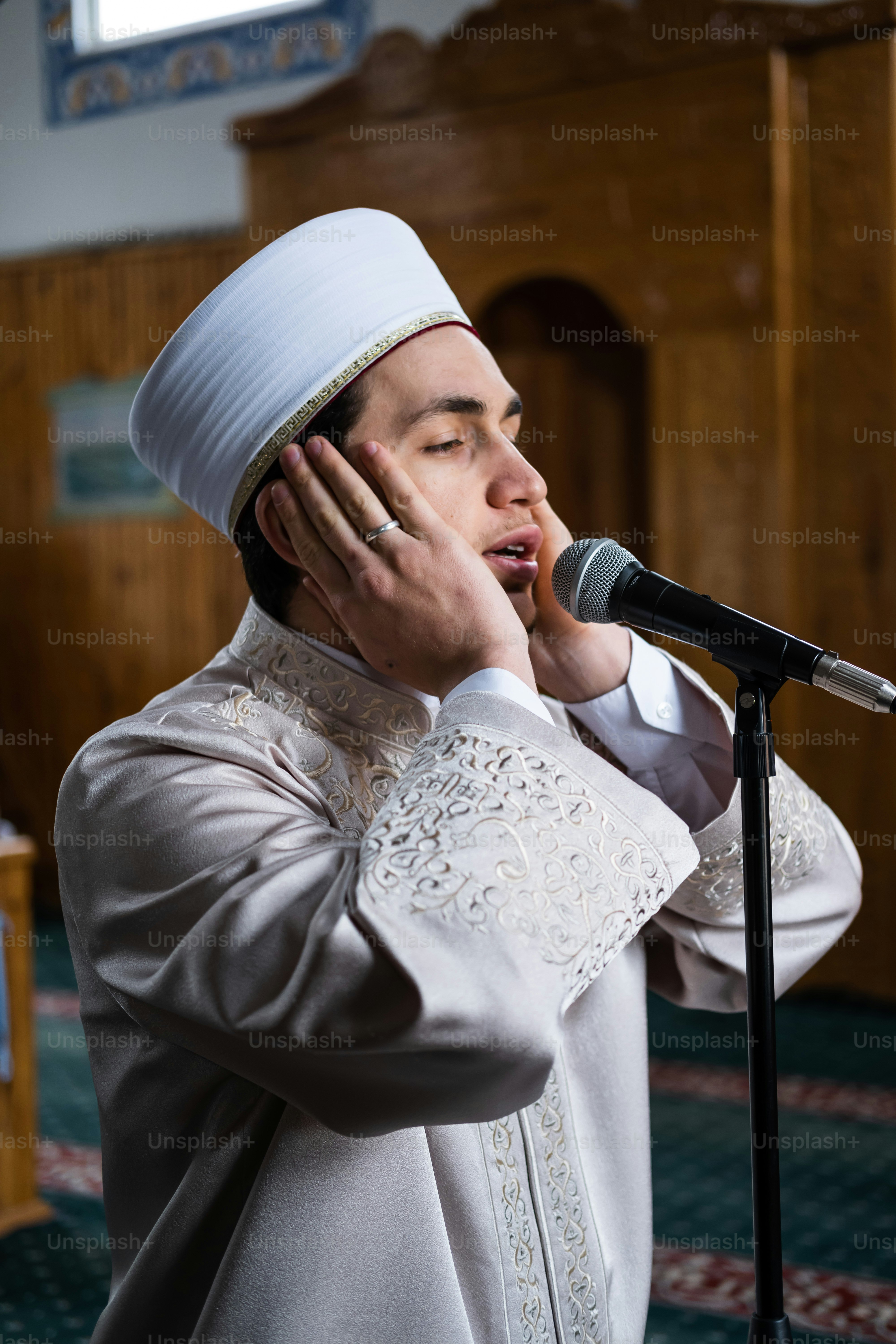Un homme en tenue blanche portant ses mains à son visage