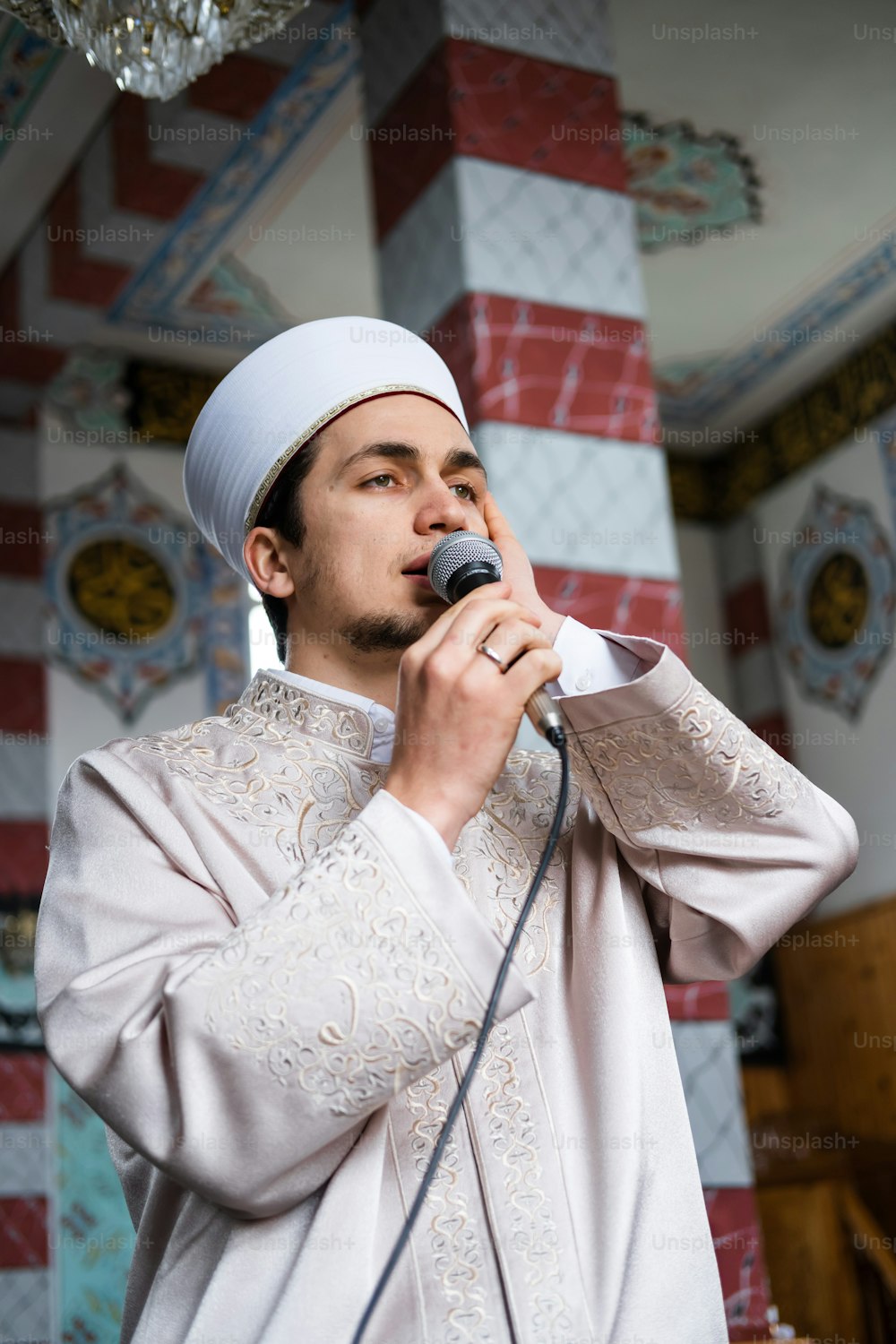 Un homme en tenue blanche chantant dans un micro