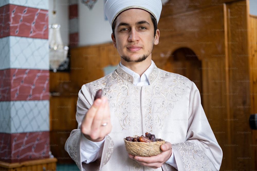 a man in a white outfit holding a bowl of food