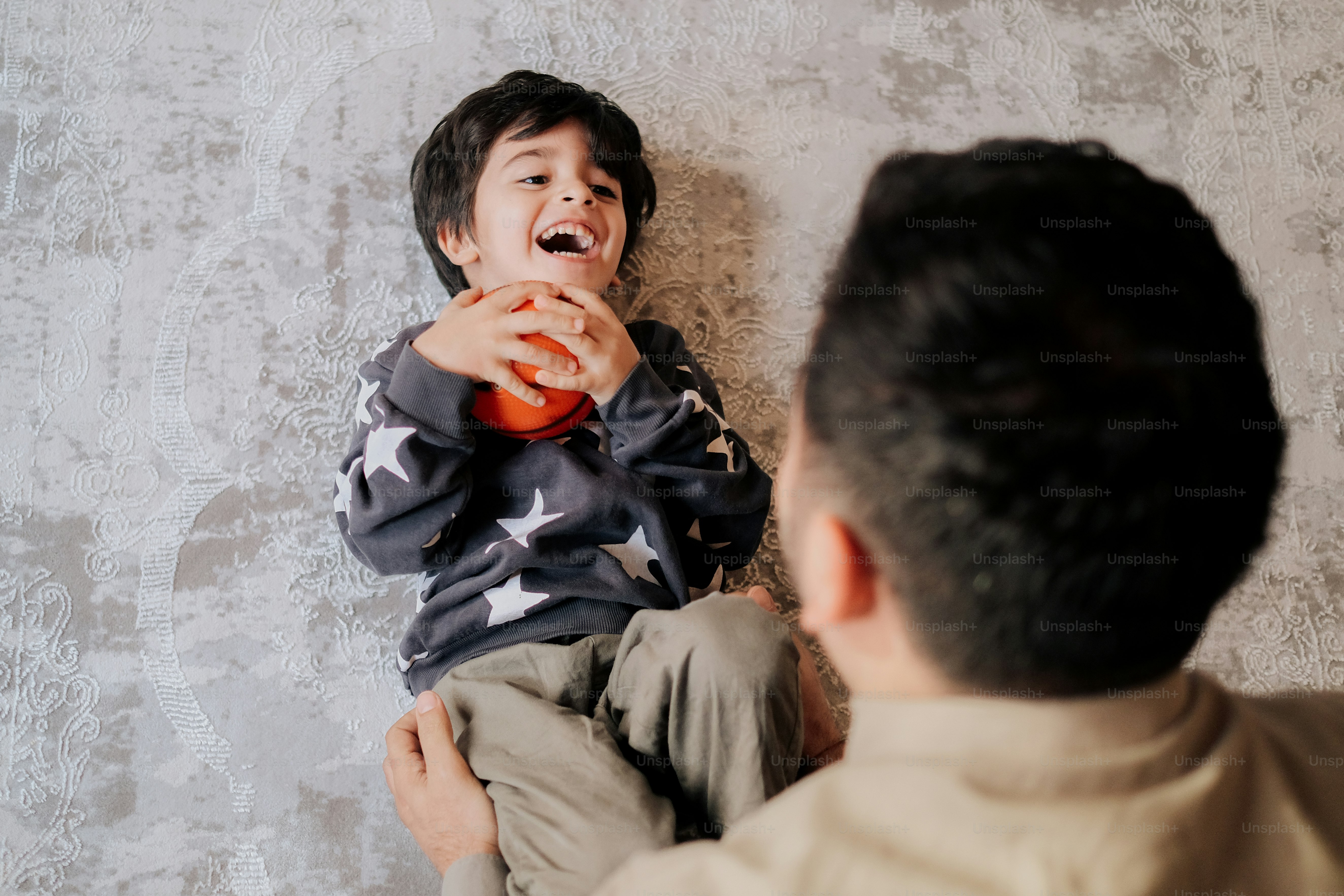 a man holding a small child in front of a wall