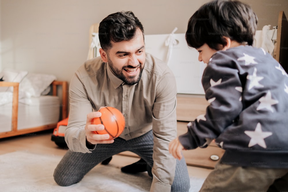 Ein Mann und ein Kind spielen mit einem orangefarbenen Ball