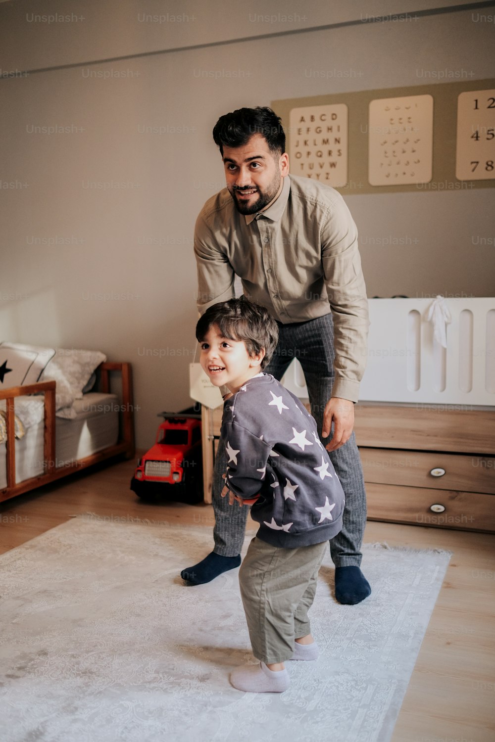 a man standing next to a little boy on top of a rug