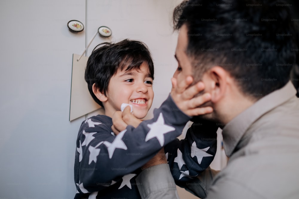 a young boy smiles as he holds his father's arm