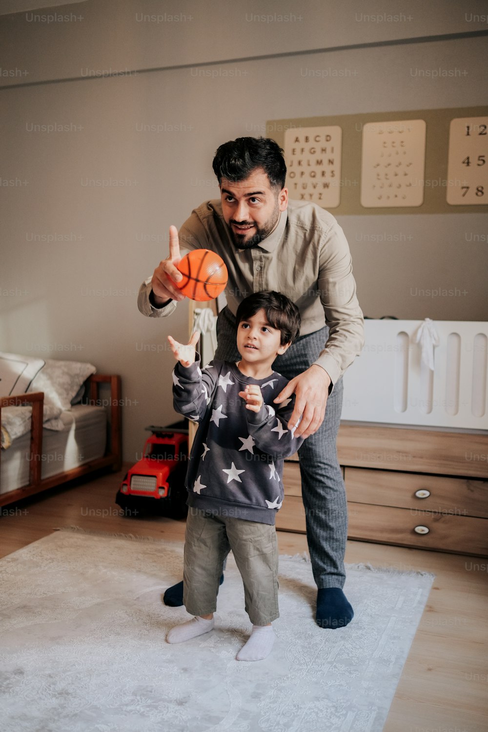 a man holding a basketball while standing next to a little boy