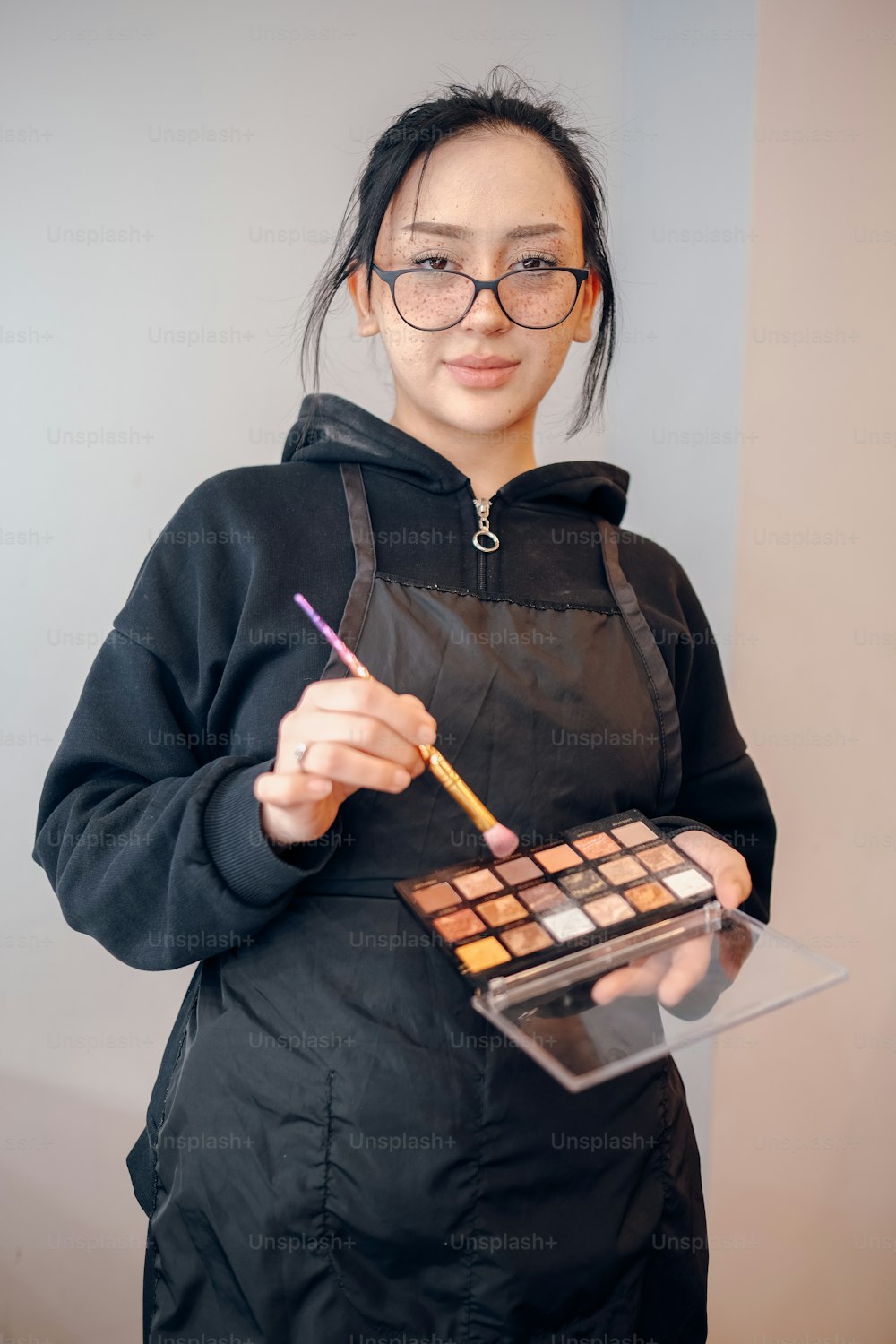 a woman is holding a palette and a pencil