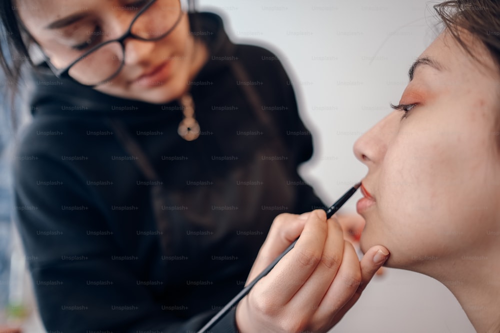 a woman getting her make - up done by another woman