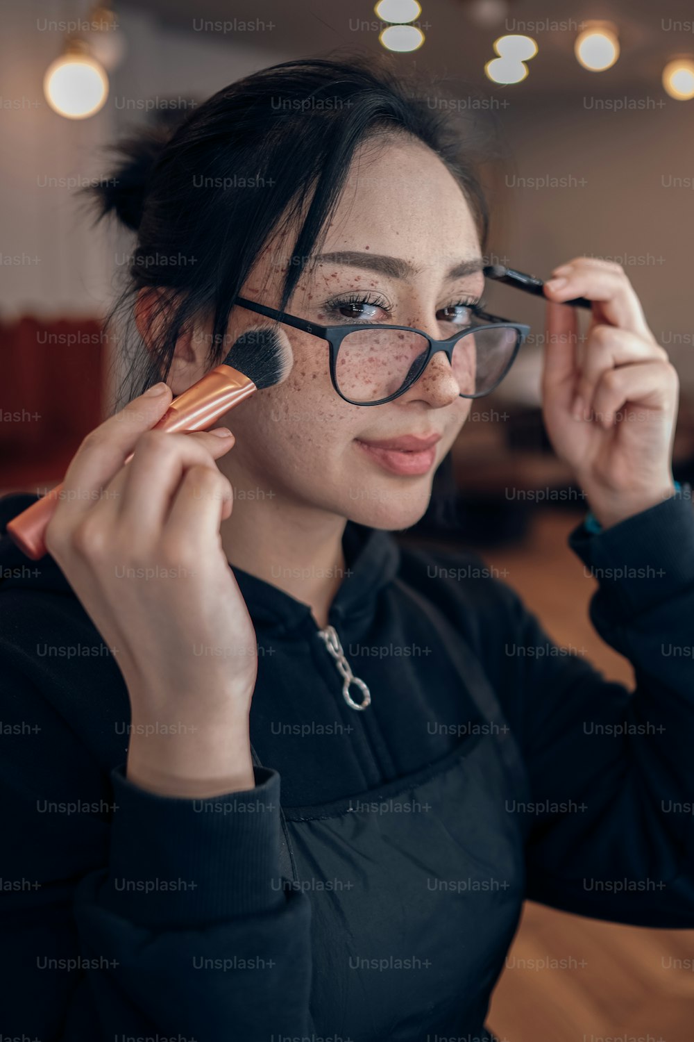 uma mulher com óculos segurando uma escova em seu olho