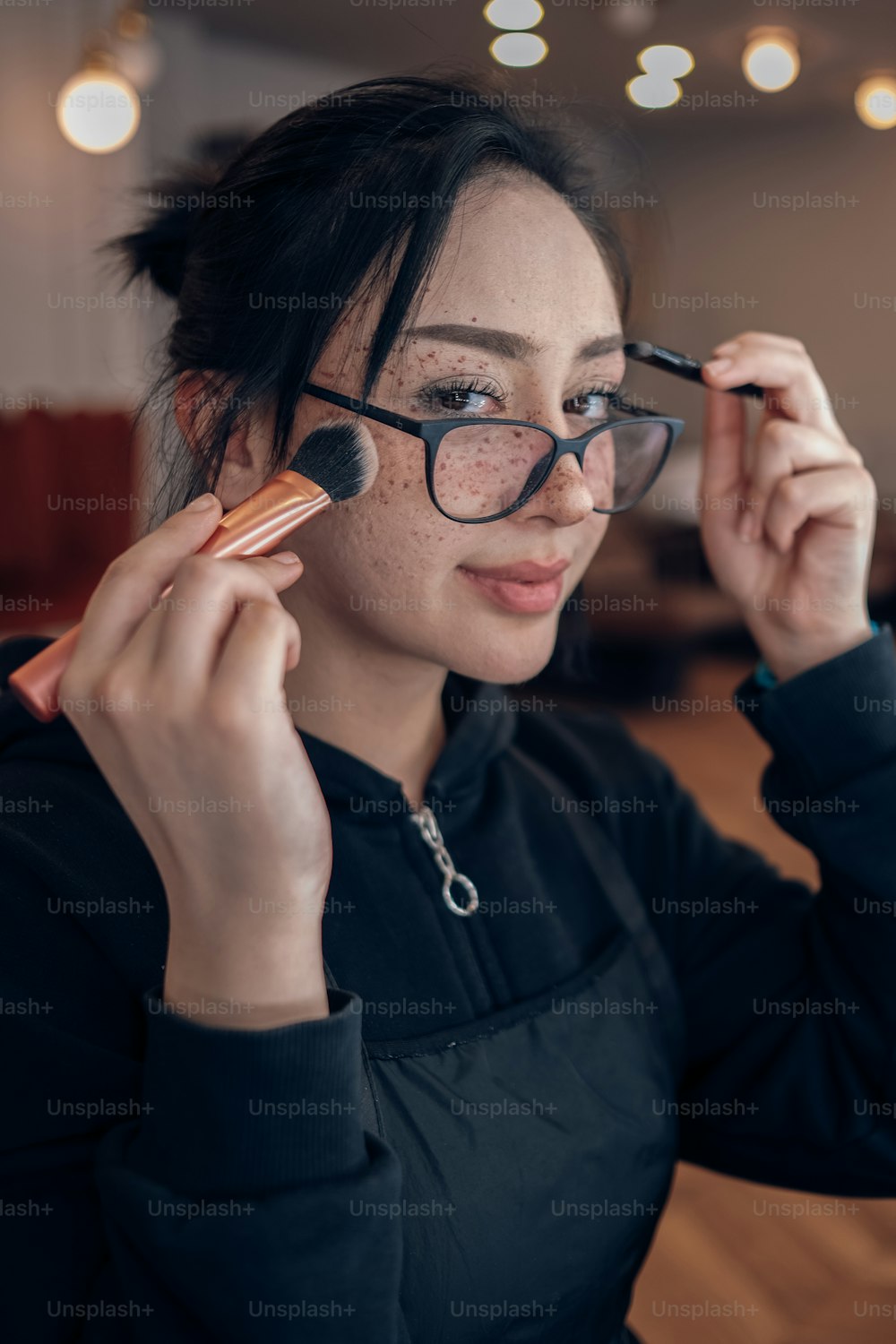a woman with glasses holding a brush to her eye
