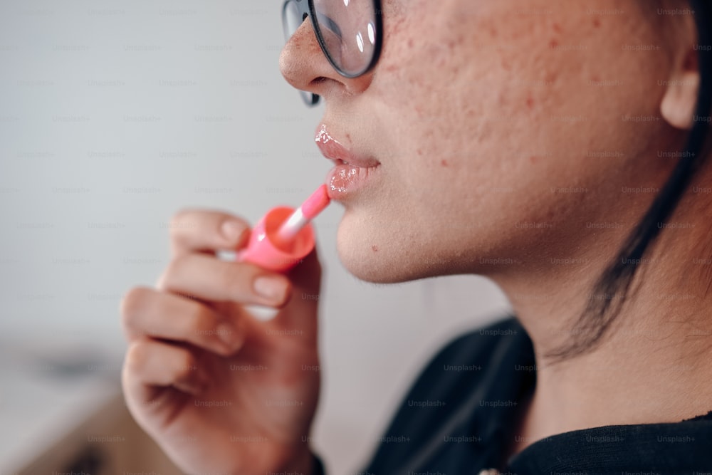 a woman brushing her teeth with a pink toothbrush