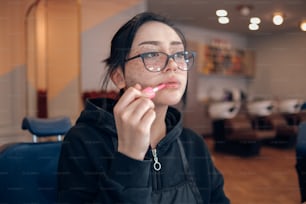 a woman with glasses is brushing her teeth