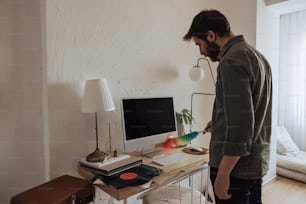 a man standing in front of a desk with a computer on it