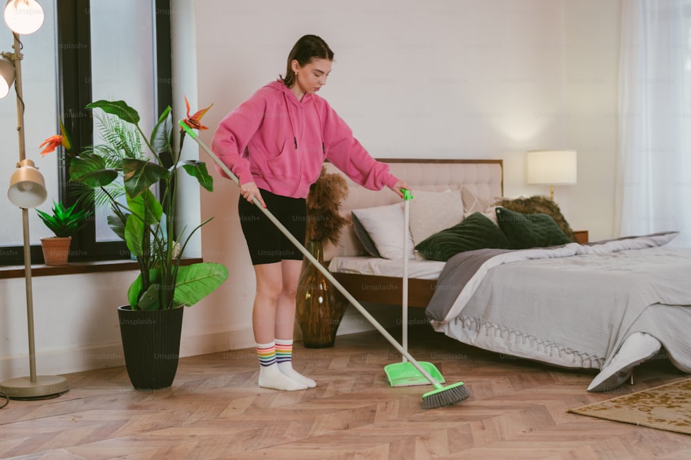 a woman in a pink shirt is cleaning a bed