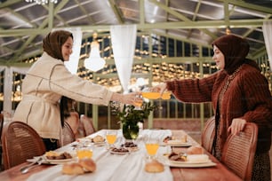 two women are shaking hands over a table