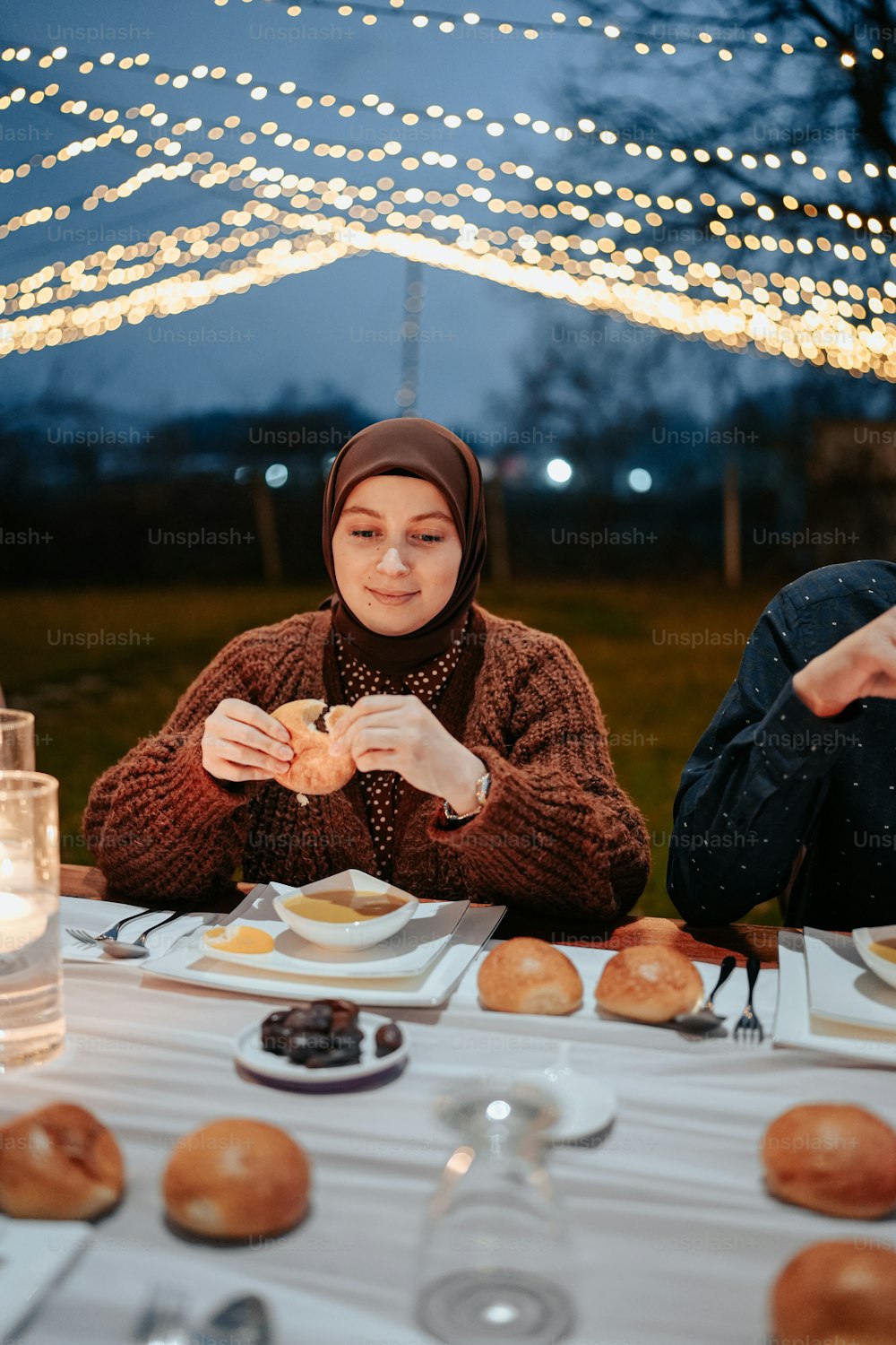 a woman sitting at a table eating a bagel