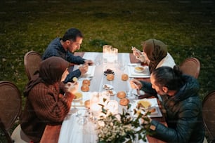 テーブルの周りに座って食べ物を食べる人々のグループ