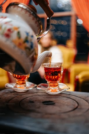 a teapot pouring tea into two glasses
