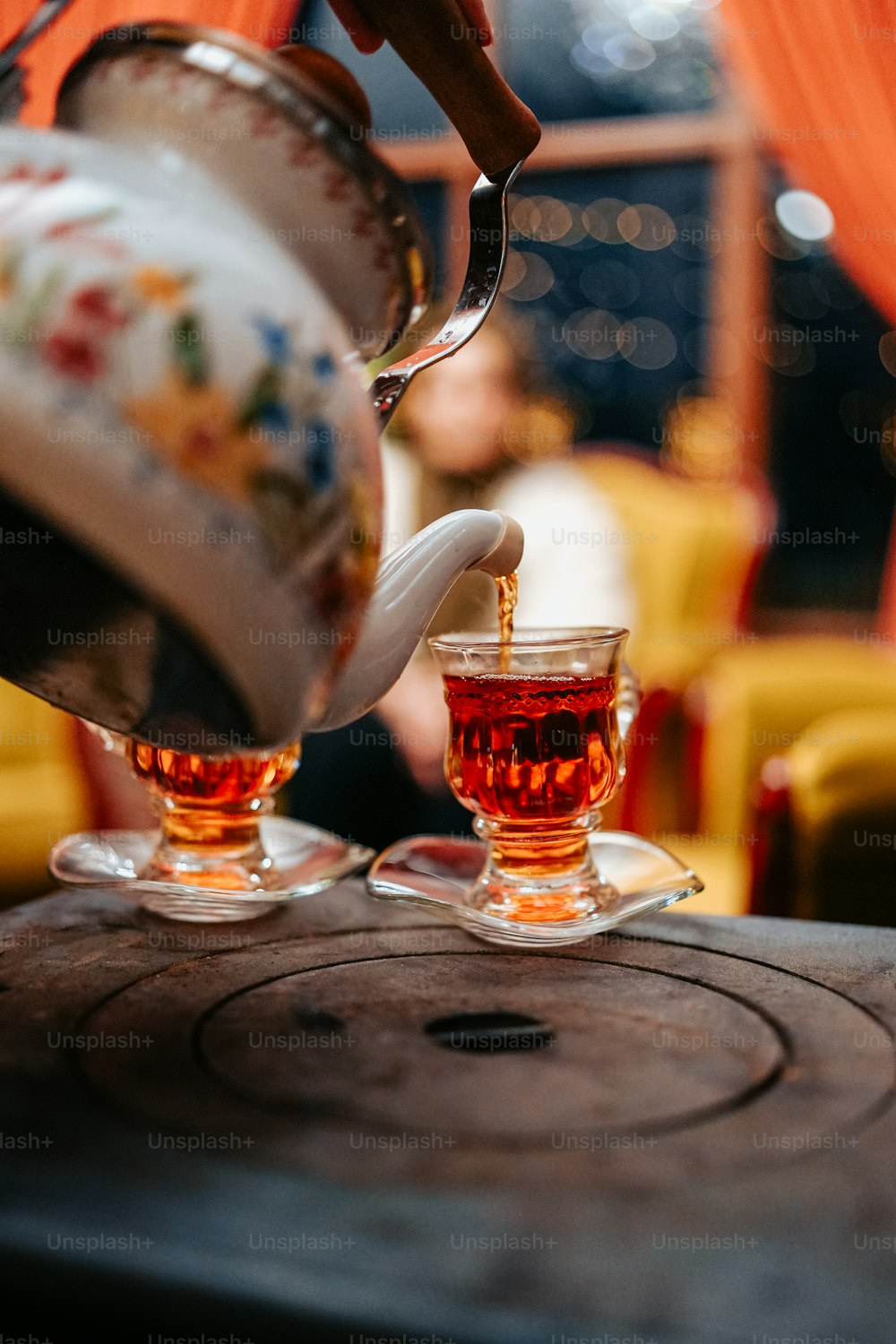 a teapot pouring tea into two glasses