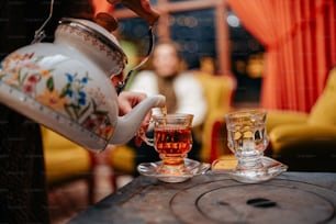 a person pouring tea into a glass cup