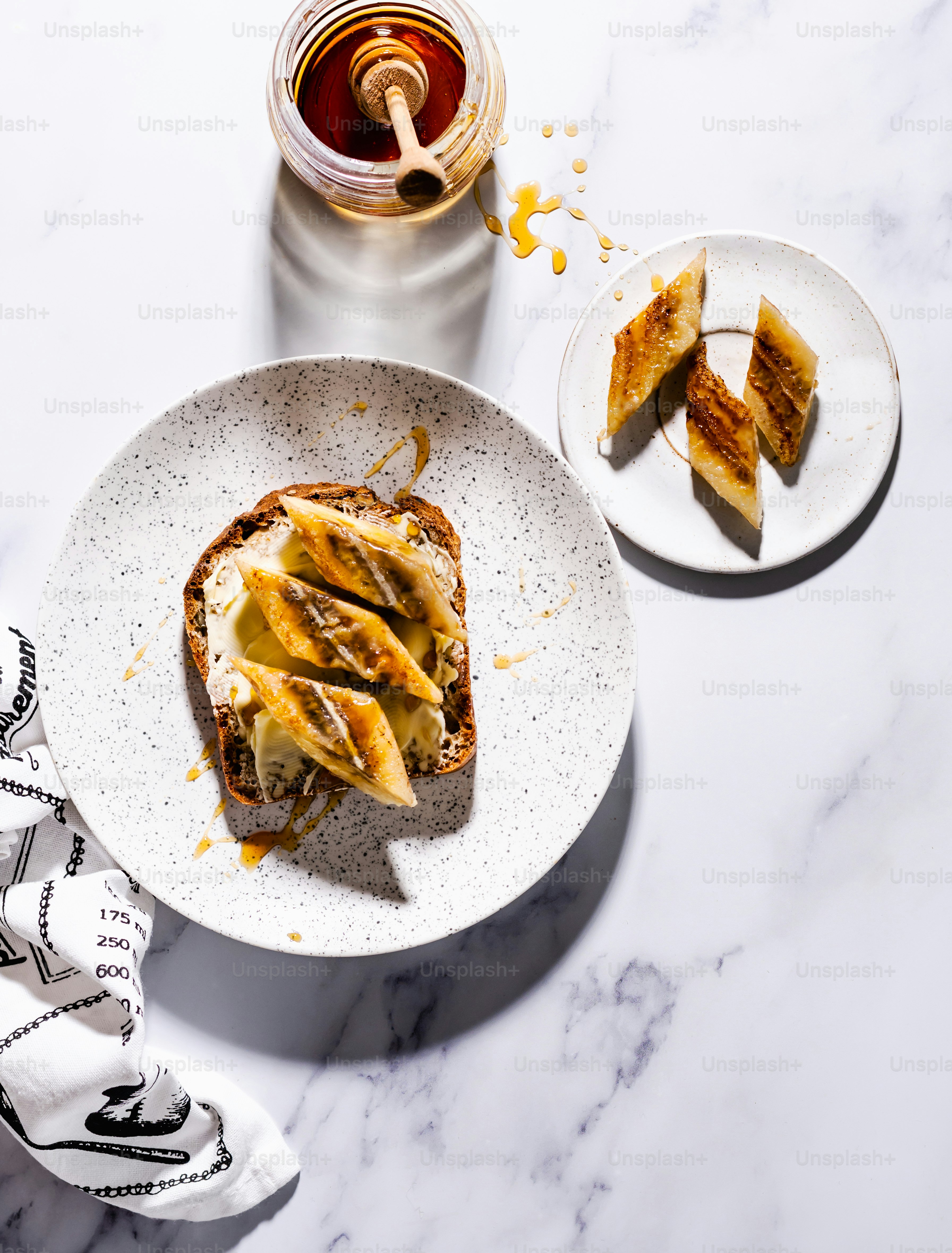 a white plate topped with a sandwich next to a jar of honey