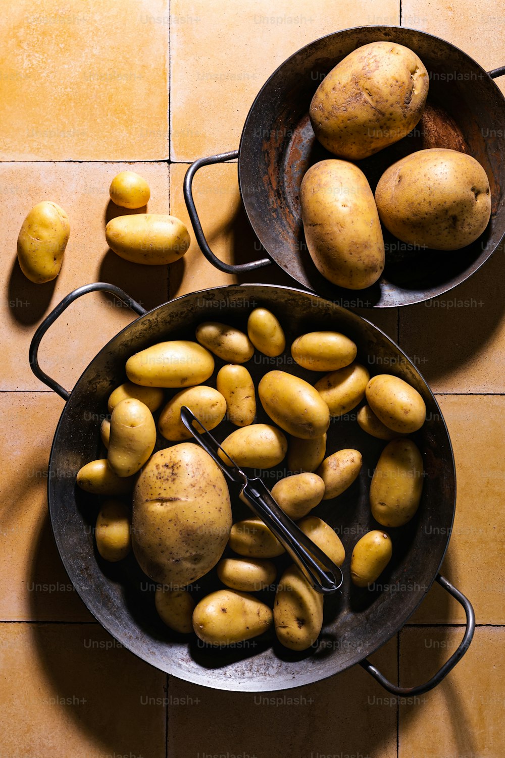 a couple of pans filled with potatoes on top of a tiled floor