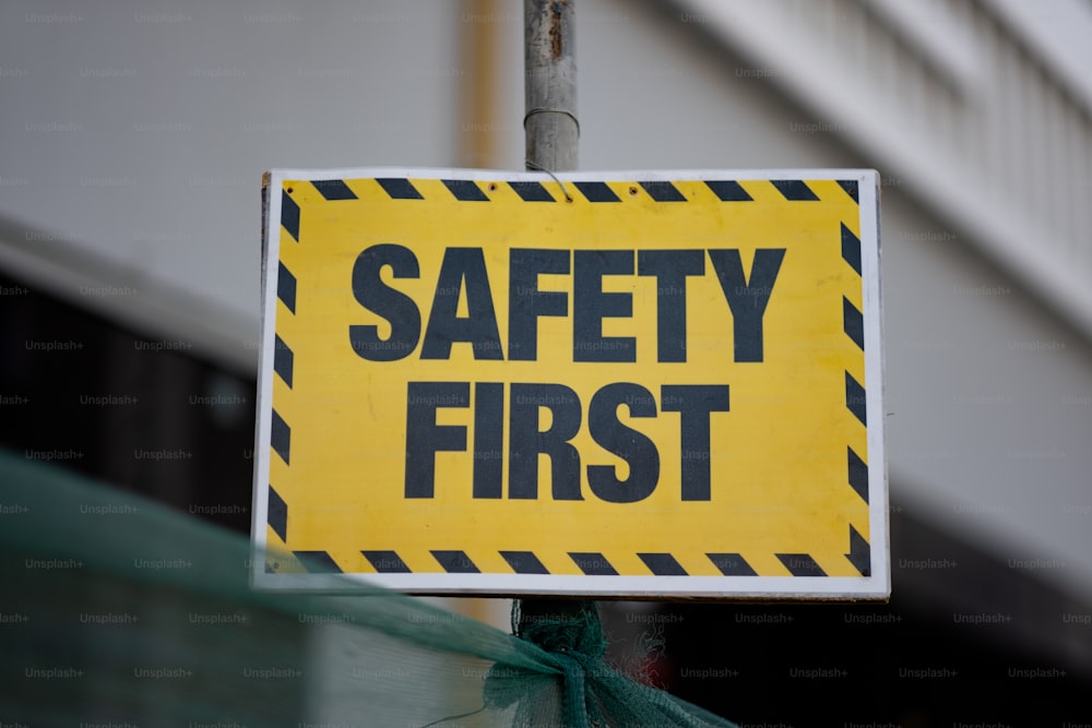 a yellow and black safety first sign on a pole