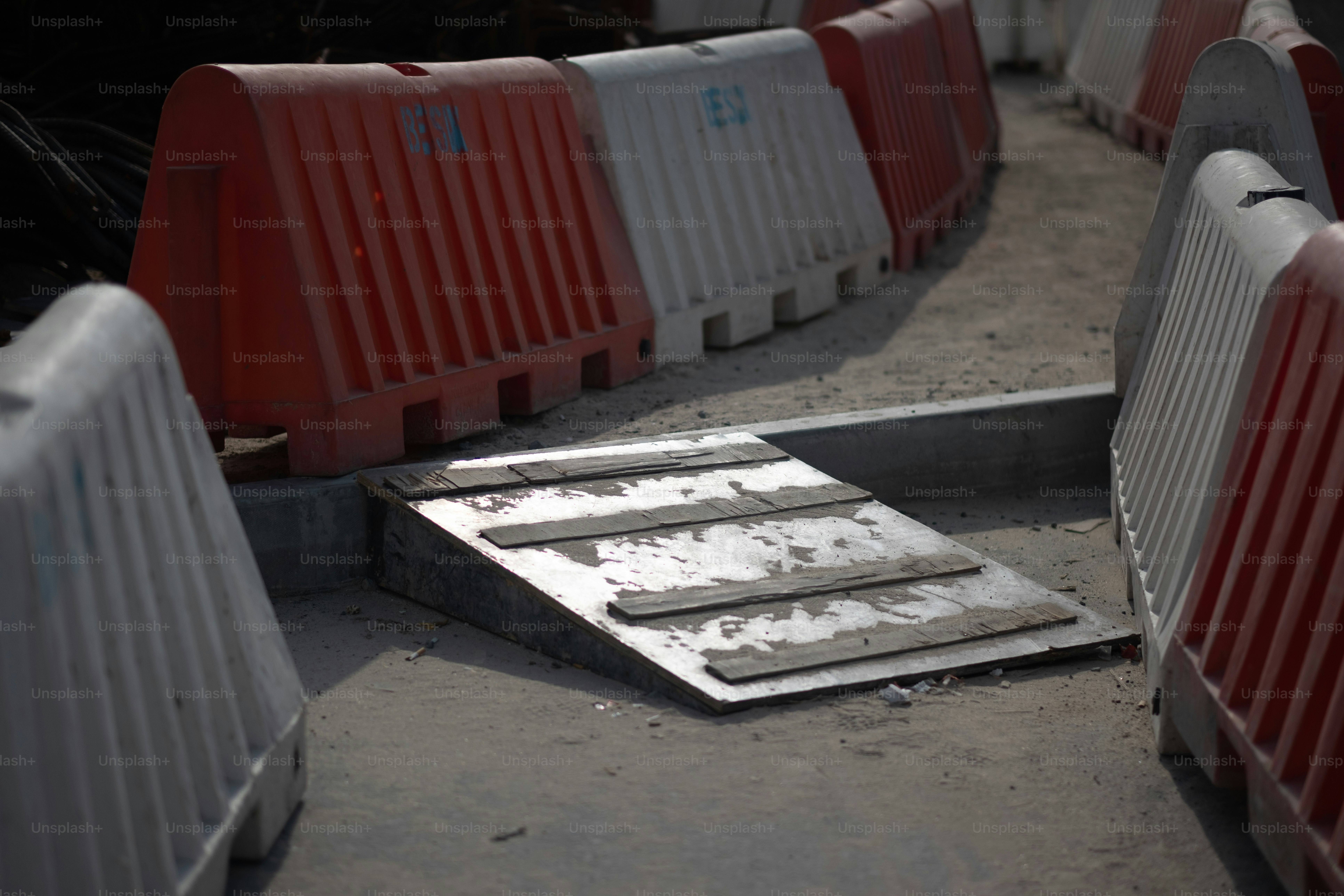 A walkway for pedestrians at a construction site, created using high-visibility red and white jersey barriers.