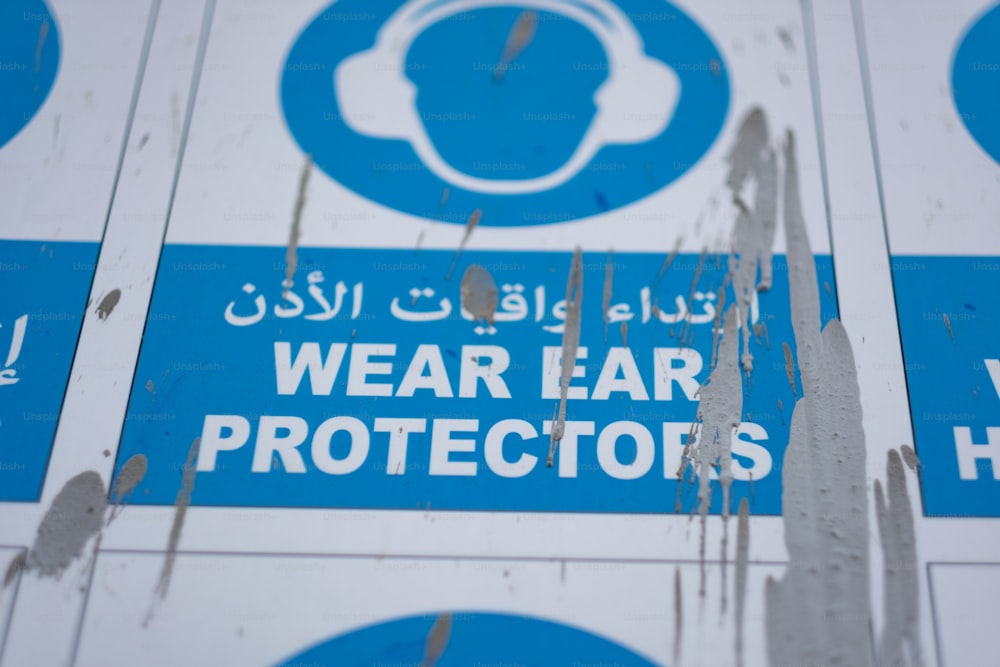 a blue and white sign that says wear ear protectors